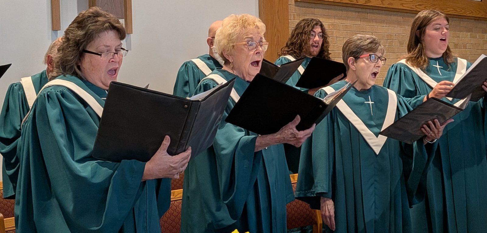 The Pathways choir in teal robes singing during Sunday worship